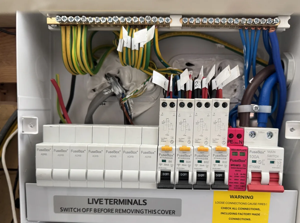 Consumer unit with its cover removed, showing wiring and protective devices during installation work