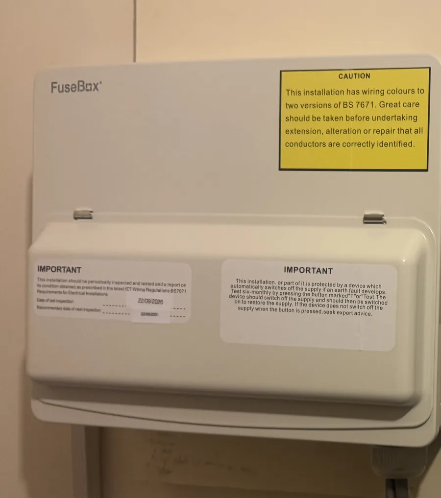 A finished consumer unit with inspection and test labels on the cover