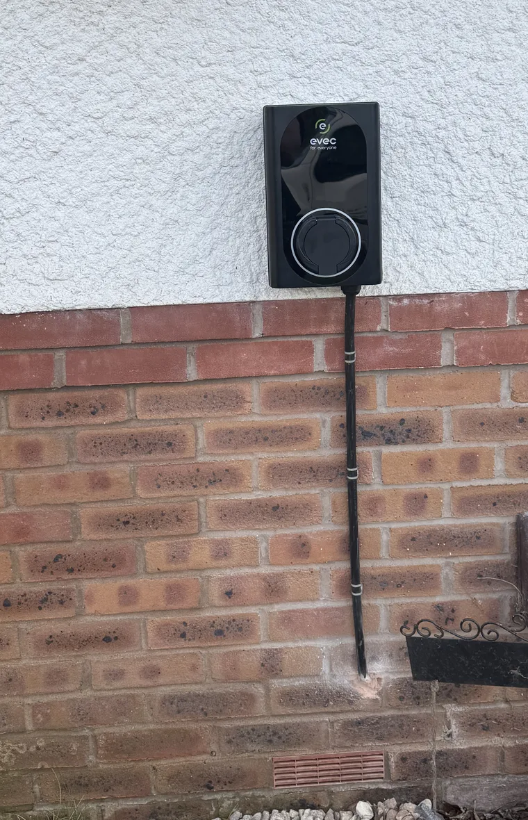 EVEC charge point fitted to a rendered exterior wall above brickwork, with a supported vertical cable route